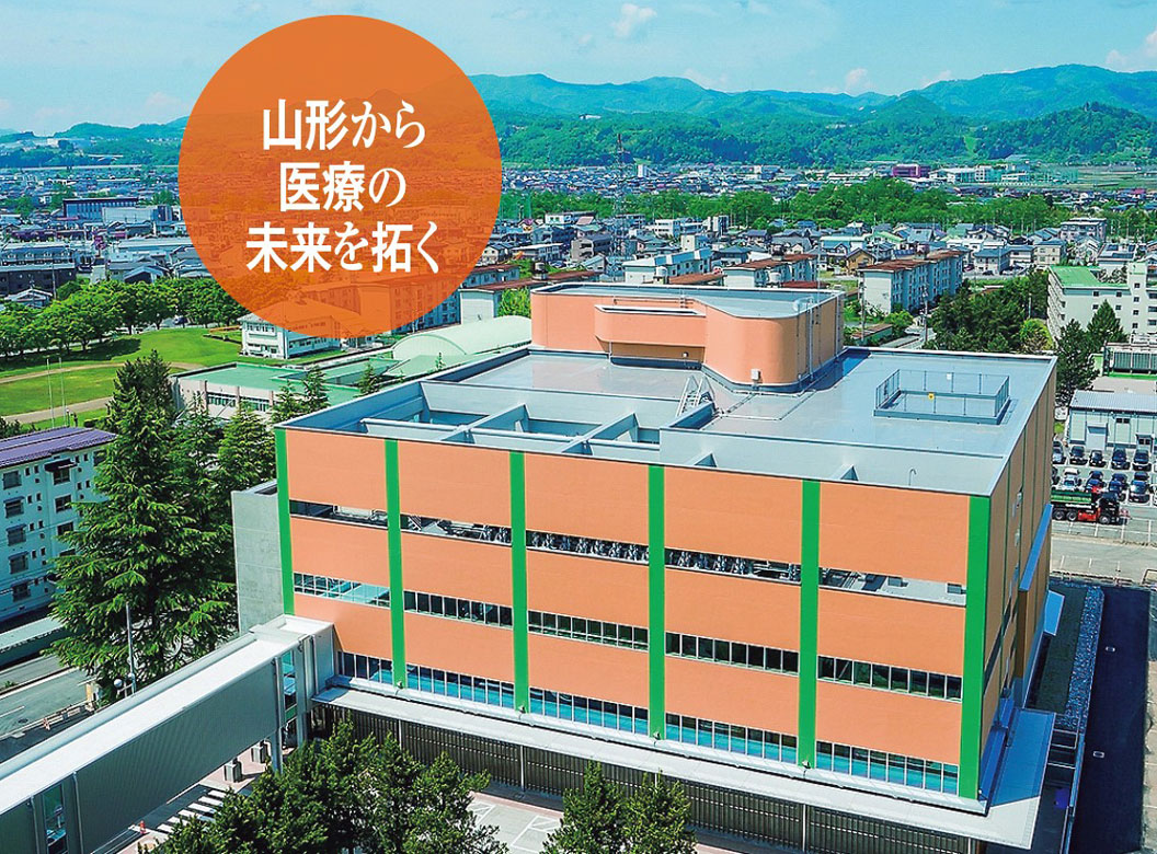 縦横ともに45メートルというキューブ型の山形大学医学部東日本重粒子センター。左前の渡り廊下（通路）で大学病院と繋がっている。