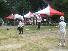 夏のキャンプに参加、子供とバトミントンする吉澤さん（左）