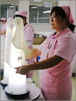 ニット製品の検品の様子で、蛍光灯の入っている棒に製品をかぶせて検品を行っている