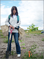 木の苗が入った袋を背負い、１本１本手作業で植えていく
